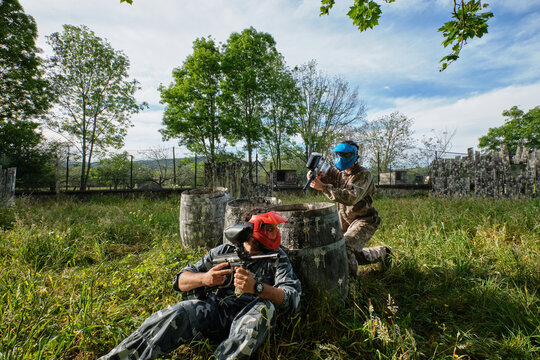 Teams in camouflage clothes playing paintball together