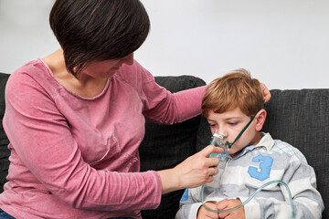 Mother putting on oxygen mask on face of child for inhalation
