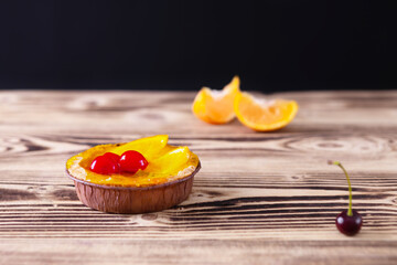 tartlets with tangerine and cherry on a wooden background. home baking, selective focus