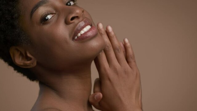 Attractive Black Woman Posing Touching Face And Neck, Beige Background