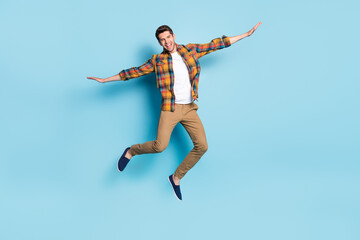 Obraz premium Photo of funny pretty young guy dressed plaid shirt spectacles smiling jumping high isolated blue color background