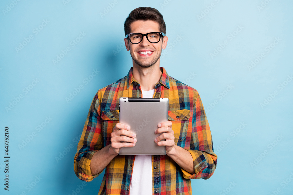 Poster portrait of attractive cheerful guy geek holding in hands using device app 5g isolated over bright b