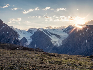 Rocky mountains with a glacier and the evening light of the setting sun. Amazing high-altitude landscape.