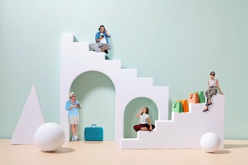 Miniature people sitting on podium.Miniature People doing different activities on podium Asian man listening music, Happy  woman with shopping bag, travel man with camera and vintage luggage.
