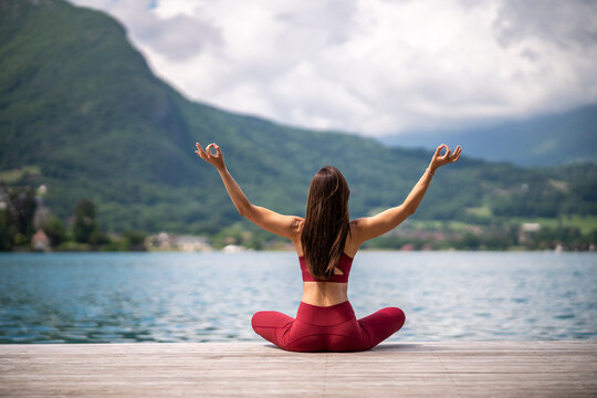Anonymous flexible woman meditating in Lotus pose on pier