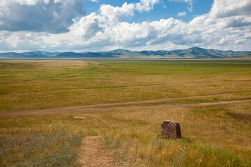Stone in the Khakass steppe. Picturesque clouds over the hills of Khakassia, Russia.