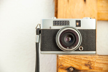 Old photo camera on a wooden stand against a white wall.