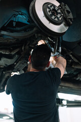 Car mechanic repair car suspension of lifted automobile at repair service station
