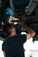 Car mechanic repair car suspension of lifted automobile at repair service station