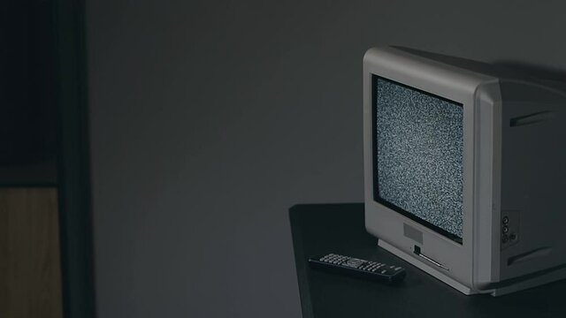 Broken Television - Old Silver TV on Black Table in Dark Room. Search for Signal. Distortion on the Screen. Close-Up, Dinamic Shot, Film Grain