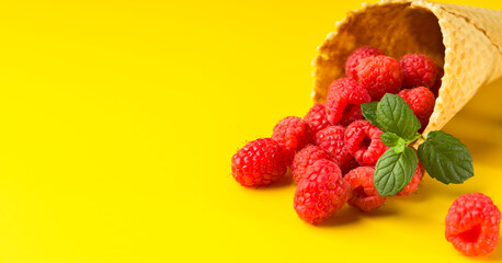 Raspberry and mint close-up in a waffle cone for ice cream on a yellow background. Healthy food concept Vegetarianism and diet.