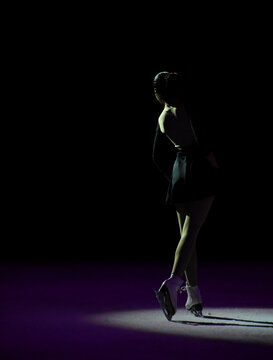 Ice skater with a beautiful pose illuminated with artistic light