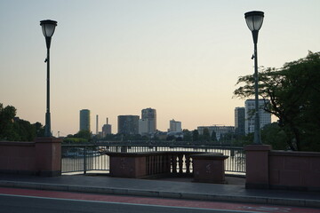 Alte Brücke mit Straßenlaternen und Blick auf Teile der Skyline im Licht der untergehenden Sonne...