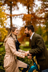 Young couple in the autumn park with electrical bicycle