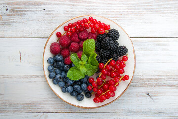 plate with fresh berries on white wooden table top view
