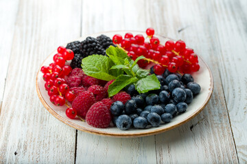 plate with fresh berries on white wooden table
