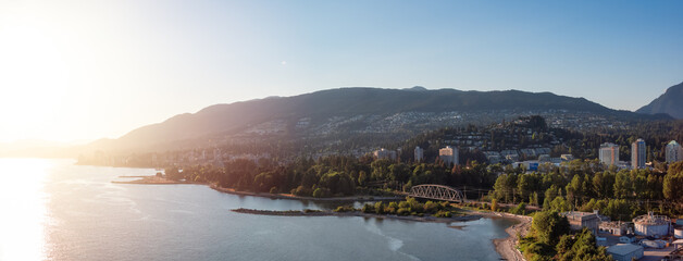 Obraz premium West Vancouver, British Columbia, Canada. Aerial Panoramic View of a modern cityscape on the Pacific Ocean Coast during an Summer sunny Sunset.