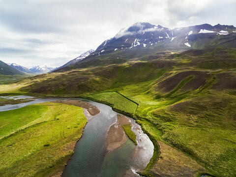 Aerial view of stream and grassland in front of a mountain, Oxnadalur, Iceland