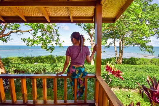 Southeast Asian, Burmese beautiful young woman sitting on the wooden ril at bungalow in Phoe Kalar island, Chaung Thar beach, Myanmar.