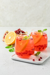 Refreshing summer iced mocktail, pomegranate citrus drink in glasses. Space for text.