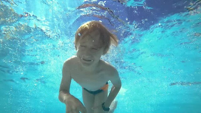 The boy dives in the pool and swims under the water