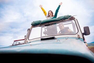 Happy man and woman travel by car in cabriolet in safari park, tour in Africa