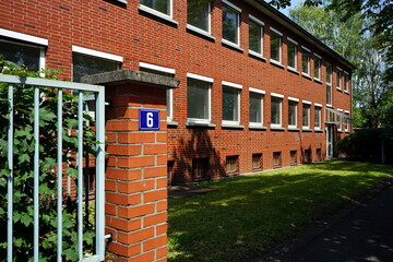 Hausnummer 6 an einem rotbraunen Backsteinbau im Grünen im Sommer bei Sonnenschein im Stadtteil...