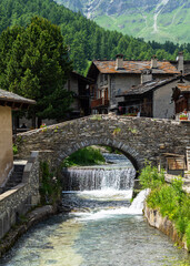 Fototapeta na wymiar The Varaita river passing under old stone bridge in the village of Chianale, Varaita Valley, Piedmont, Italy