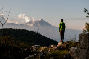 rear view of woman standing on big stone against beautiful mountain landscape