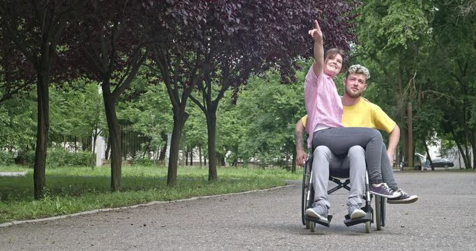 Young man in wheelchair and his wife outdoors