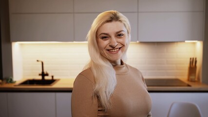 Smiling attractive young adult woman model looking at camera, happy beautiful blonde lady professional pretty face dental smile posing stand alone indoors, close up view portrait	