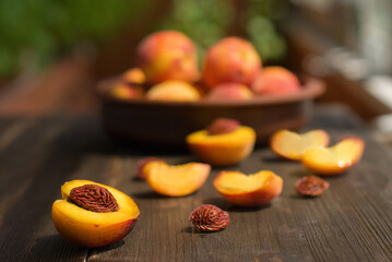 Family wooden kitchen table with peaches cut into halves scattered all over it after the harvest. Cooking breakfast.