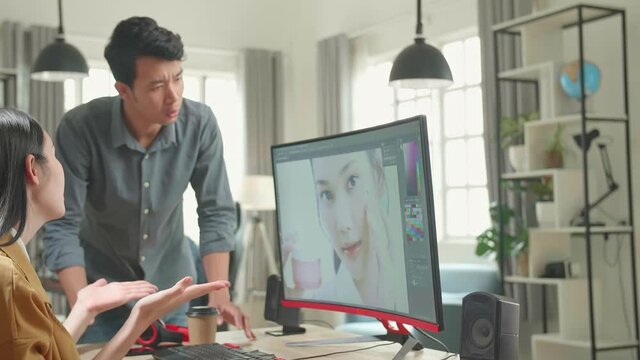 Asian Male And Female Professional Editors Arguing While Working In Photo Editing App / Software On A Personal Computer. Photo Editors Retouching Photos Of A Beautiful Girl
