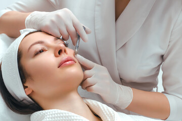 Lip augmentation and correction procedure in a cosmetology salon. The specialist makes an injection...