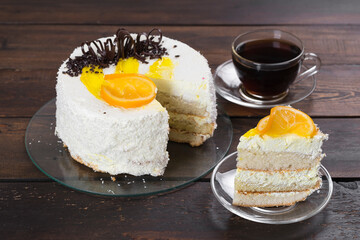 Creamy orange cake on a wooden table. A cup of coffee