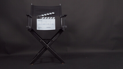 Clapper board or movie slate with director chair use in video production and cinema industry.It is put on black background.