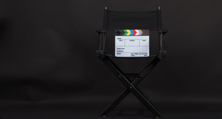 Clapper board or movie slate with director chair use in video production and cinema industry.It is put on black background.