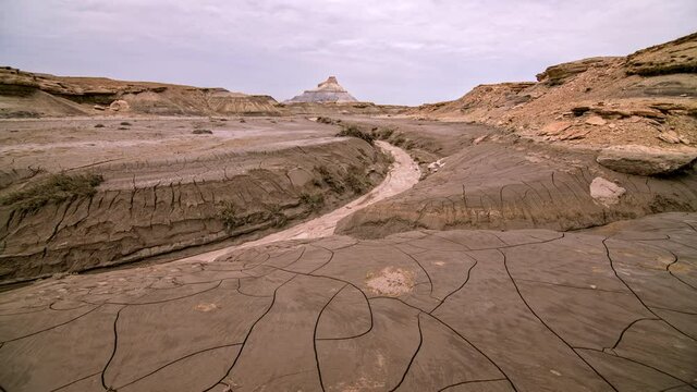 Overlooking cracked mud landscape drying out after flash flood at Factory Butte in timelapse in the Utah desert.