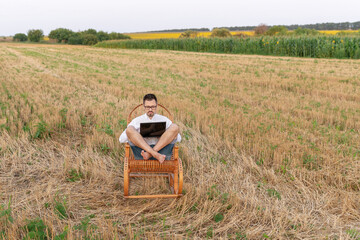 Man working remotely outdoors with notebook on beveled field. Using laptop computer in nature, technology and freedom concept. Freelance and online education.