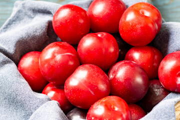 Chinese or Korean red plum in a basket on the table closeup. Summer or autumn harvest	
