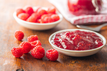 Red rasberries jam in bowl and ripe raspberries.