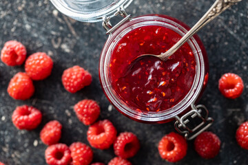 Red rasberries jam in jar and ripe raspberries.