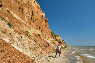 young man and backpack walks alone along a sand hill