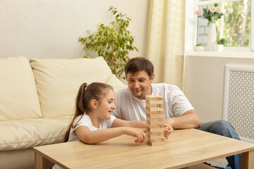 Happy family and cute little girl excites with wooden block game