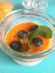 pannacotta dessert with mango and blueberry in jar. served at blue napkin
