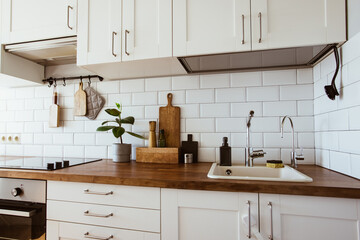 Kitchen brass utensils, chef accessories. Hanging kitchen with white tiles wall and wood...