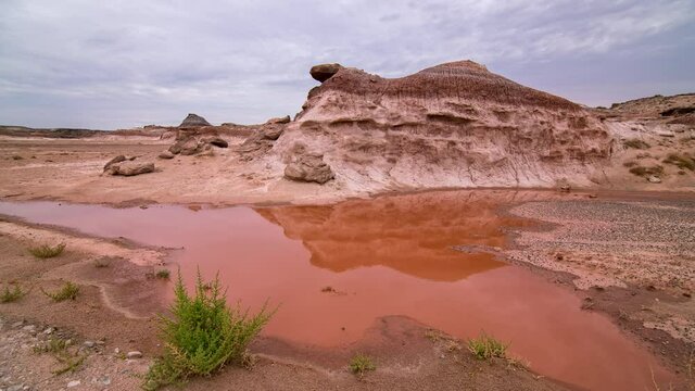 Timelapse moving over puddle of red water in the mars like desert in Utah after rainstorm during the summer monsoon.