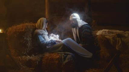 Joseph talking with Mary and baby Jesus in barn nativity scene