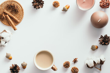Autumn composition. Flat lay coffee cup, candles, cinnamon sticks, cones, acorns on white background. Nordic, hygge, cozy home concept