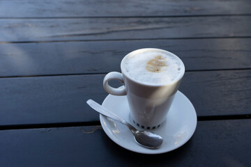 Cup of coffee with milk, on wooden table in black color